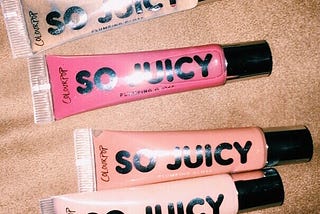 Four So Juicy lip glosses from Colourpop. The colors are clear, pink, tan, and a sparkly pink.