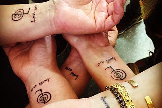 Five white people’s wrists, displaying tattoos