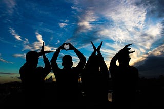 Four people raising their hands, each in their unique manner.