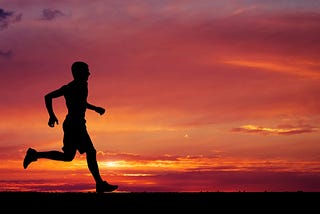 Male runner silhouetted against fiery horizon