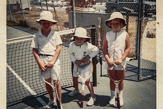 Three kids in the 70s on a tennis court in tennis attire