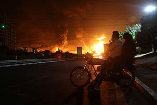 People watch as a fire burns at the Sharan oil depot following Israeli strikes in Tehran, Iran, June 15, 2025. Photo by Majid Asgaripour/WANA (West Asia News Agency) via Reuters