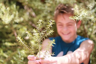 A happy young man has picked a herb from the garden.