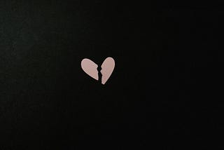 Broken pink heart on black background