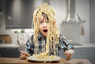 Young boy with whole head covered in spaghetti