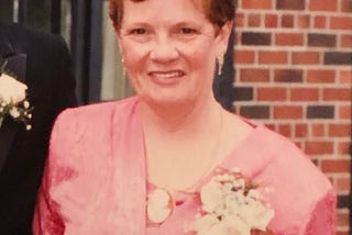 Terry Lenkner in 1987 wearing a pink dress and smiling in front of a red brick building in Toronto.