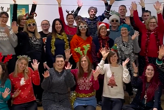Sale Sings community choir members, all dressed up for our Christmas gig, smiling and waving.