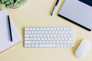 White Apple Keyboard and Computer with Yellow Background