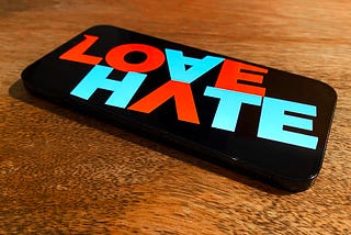 An iPhone 12 Pro Max with the words LOVE and HATE on the screen.