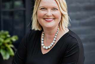 Amy Leneker photo wearing a black blouse and white necklace.