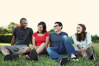Two couples sitting on grass smiling