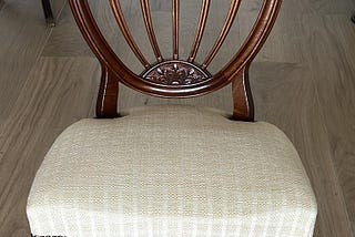 An antique chair featuring a padded cushion and some wood-carved details.