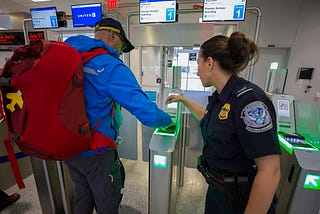 A photograph of a passenger at George Bush Intercontinental Airport in Houston, US, who is scanning their ticket at a biometric station to board a flight