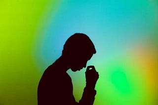 Silhouette of a person thinking in front of a blue and green background.