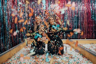 Two girls playing around with confetti.