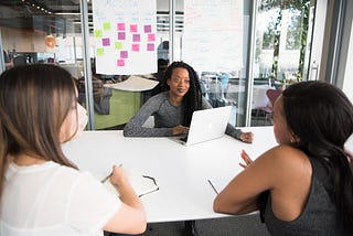 Three women in an office meeting room having a conversation