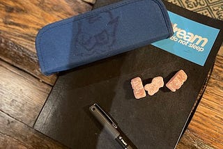 Three Jelly Babies and an insulin pen-holder sitting on a notebook