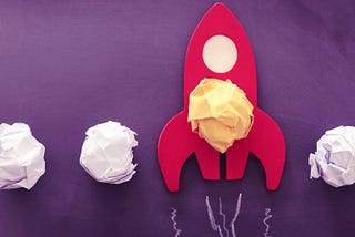 Cutout rocket ship with scrunched up post-it notes, signifying launching or boosting an idea