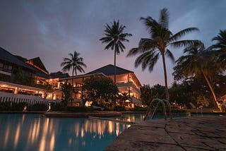 A fancy mansion with a swimming pool and palm trees.