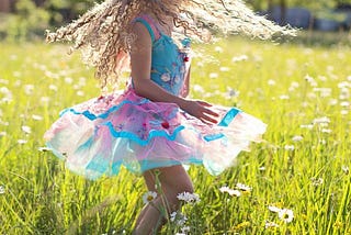 Girl in frock swirling in a flowery field