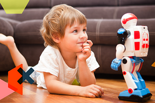 Image of a young boy lying on the floor, talking to his toy robot.