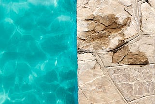 Beige stones with large darkened patches next to a body of water