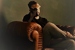 Man in a chair with his hand over his face.