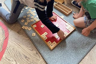 Our oldest teaching his little sister “The Hundred Board” which is a key Montessori Mathematics material.