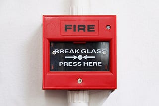 Closeup view of a fire alarm that says ‘break glass — press here’