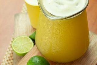 A yellow pitchure of lemonaide on a cutting bord.