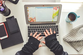 Writer at a computer wearing black fingerless gloves