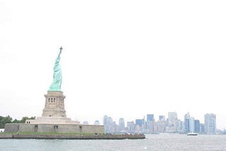 The Statue of Liberty stands on the left with the New York City skyline behind. The photo was taken in 2003 so the World Trade Center towers are missing .