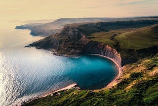 An aerial image of a green cliff overlooking the beautiful blue sea.