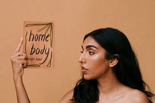 Poet Rupi Kaur holding her newest poetry book, Home Body