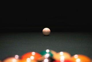 Colorful balls set up on a pool table; the white ball is prepared for the shot.