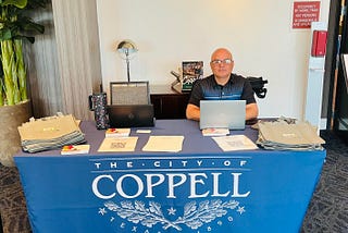 Luay Rahil sitting behind a table while hosting a job fair at the city of Coppell.