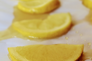 Frozen lemon slices covered in honey lying on parchment paper.