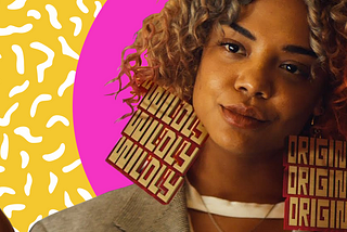 Tessa Thompson’s character “Detroit” wearing earrings that state “Wildly” on the left earring and “Original” on the right earring.