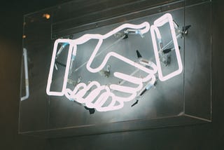 Neon light display creating the outline of a handshake