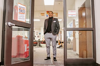 Cameron smiles for a photo at the entrance of the TRIO office