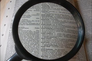 A magnifying glass focusing on a page in the dictionary