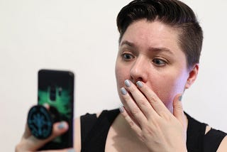 A woman staring at her phone in shock after hearing bad news.