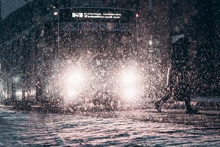 Person running across the street while a bus is coming in the snow.