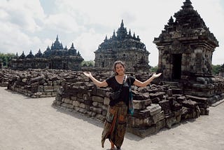 a woman (me) smiling and making the “I don’t know” gesture in front of a temple in Java, Indonesia