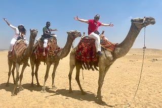 Author Jeffrey Kass with two friends on camels near the Pyramids in Egypt