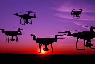 Five drone silhouettes in the sky at sunset