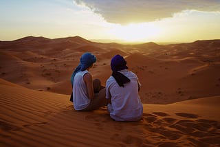 two people on a sand dune in the desert together. that could be you and me.