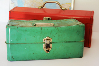 Photo of two colourful metallic toolboxes, a green one and a red one.
