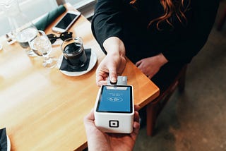 Customer using mobile payment tech in a coffee shop.