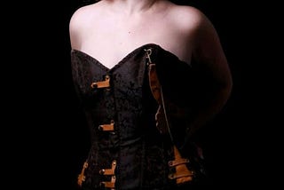 A photo of a white Irish woman wearing a brown textured corset looking away from the camera